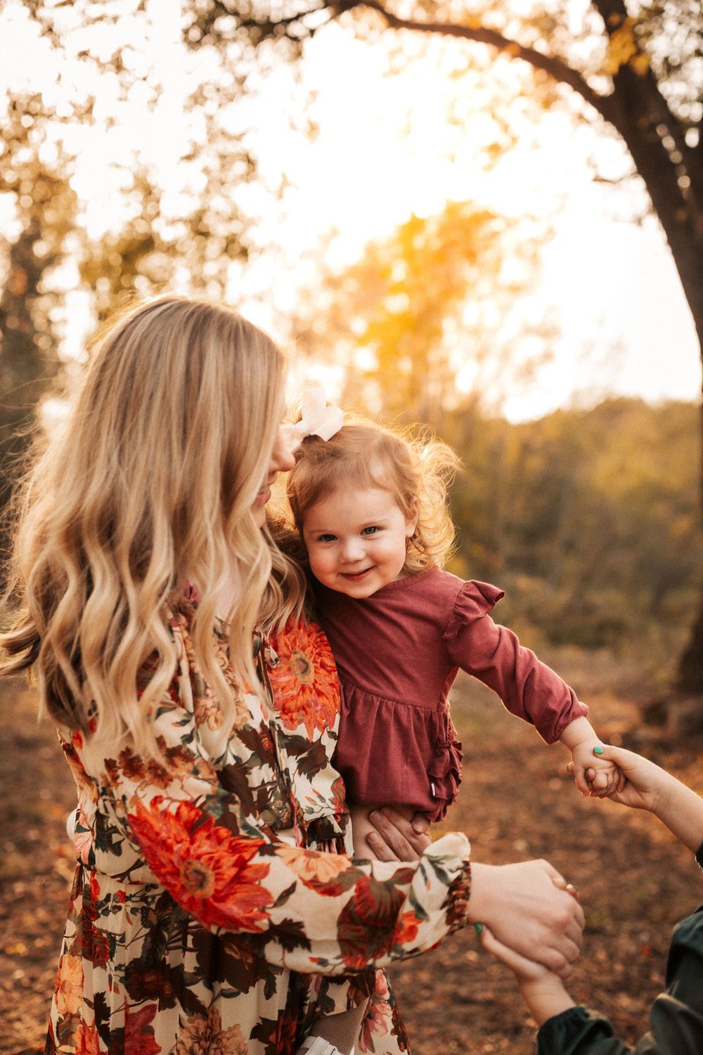 A tender moment captured in warm autumn lighting as family members share a playful dance in the woods.