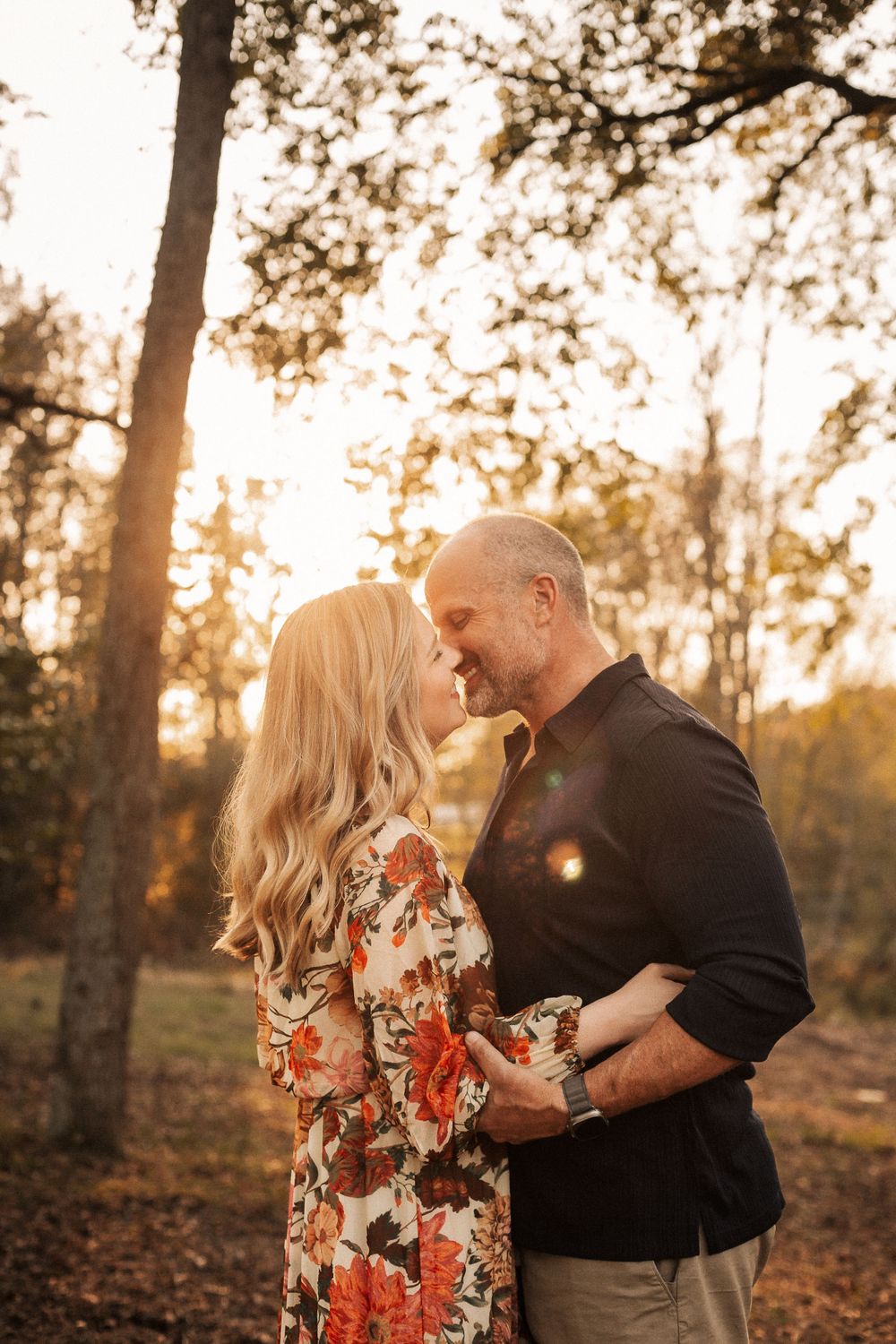 A romantic sunset portrait of a couple sharing an intimate moment in a forest setting.