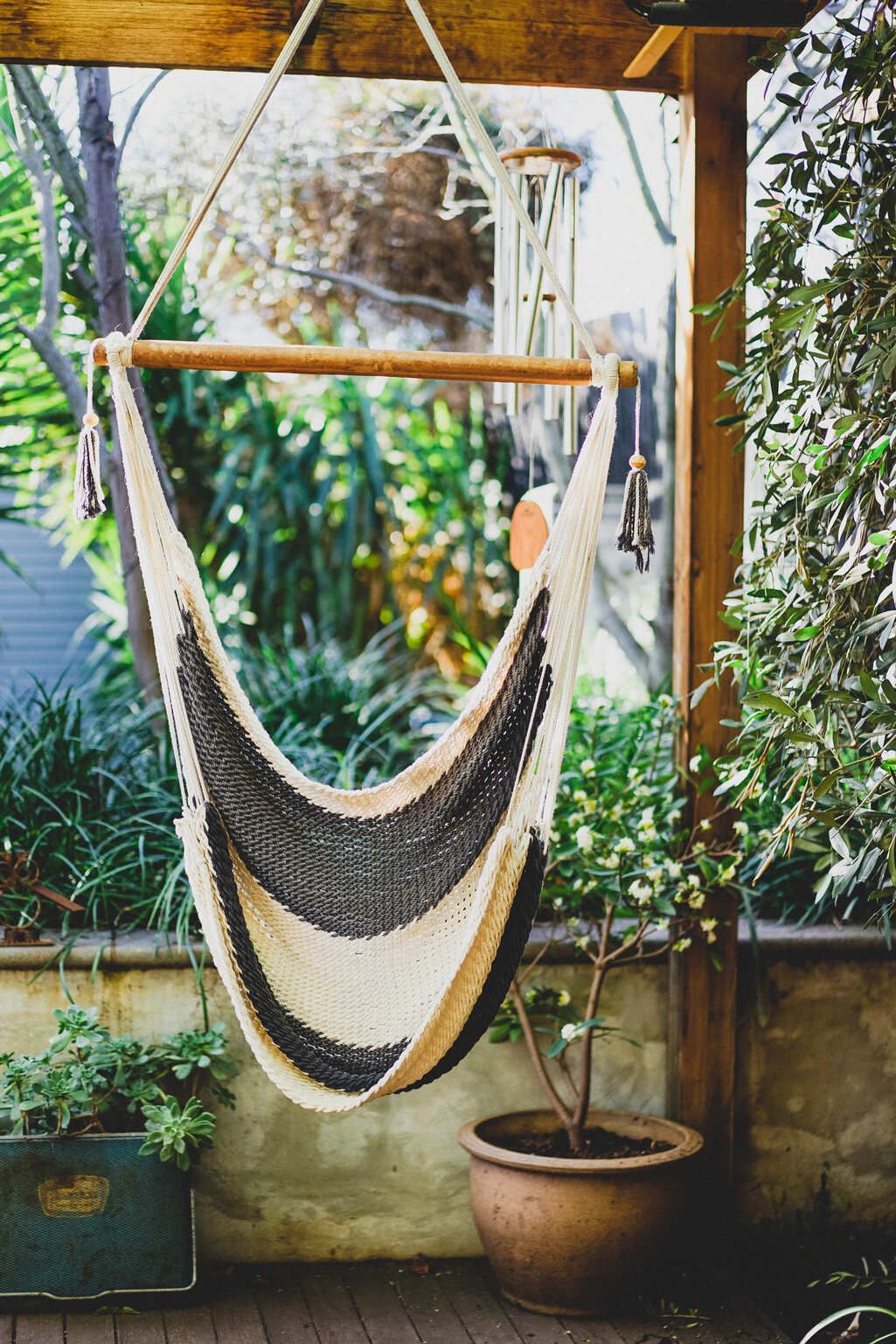 Macrame hanging chair with striped pattern suspended on wooden porch.