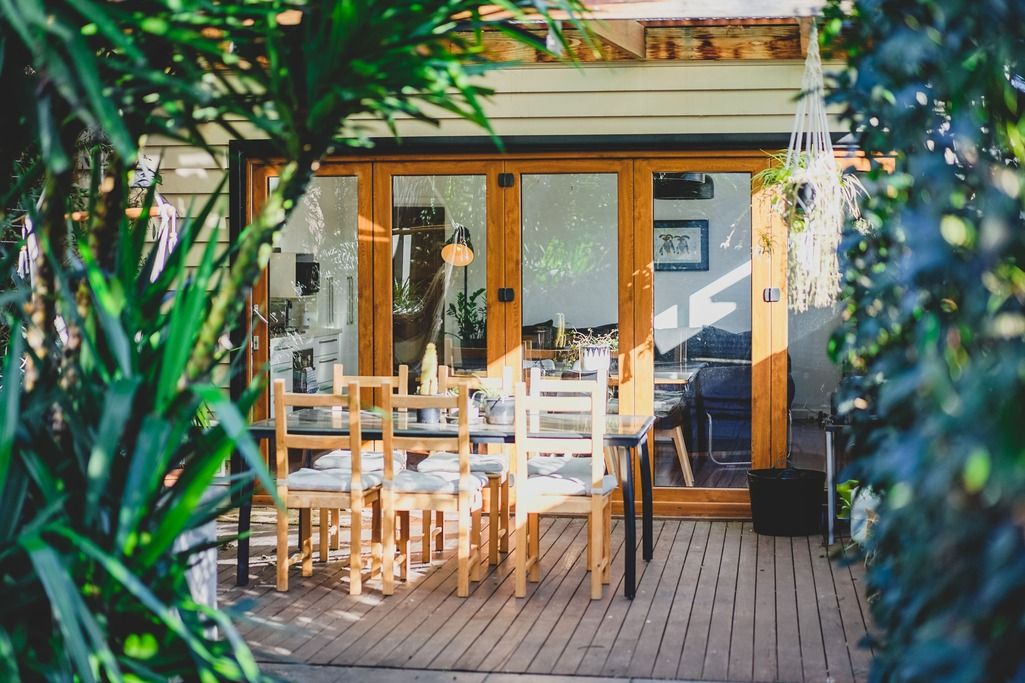 Cozy wooden deck with outdoor furniture framed by lush tropical plants.