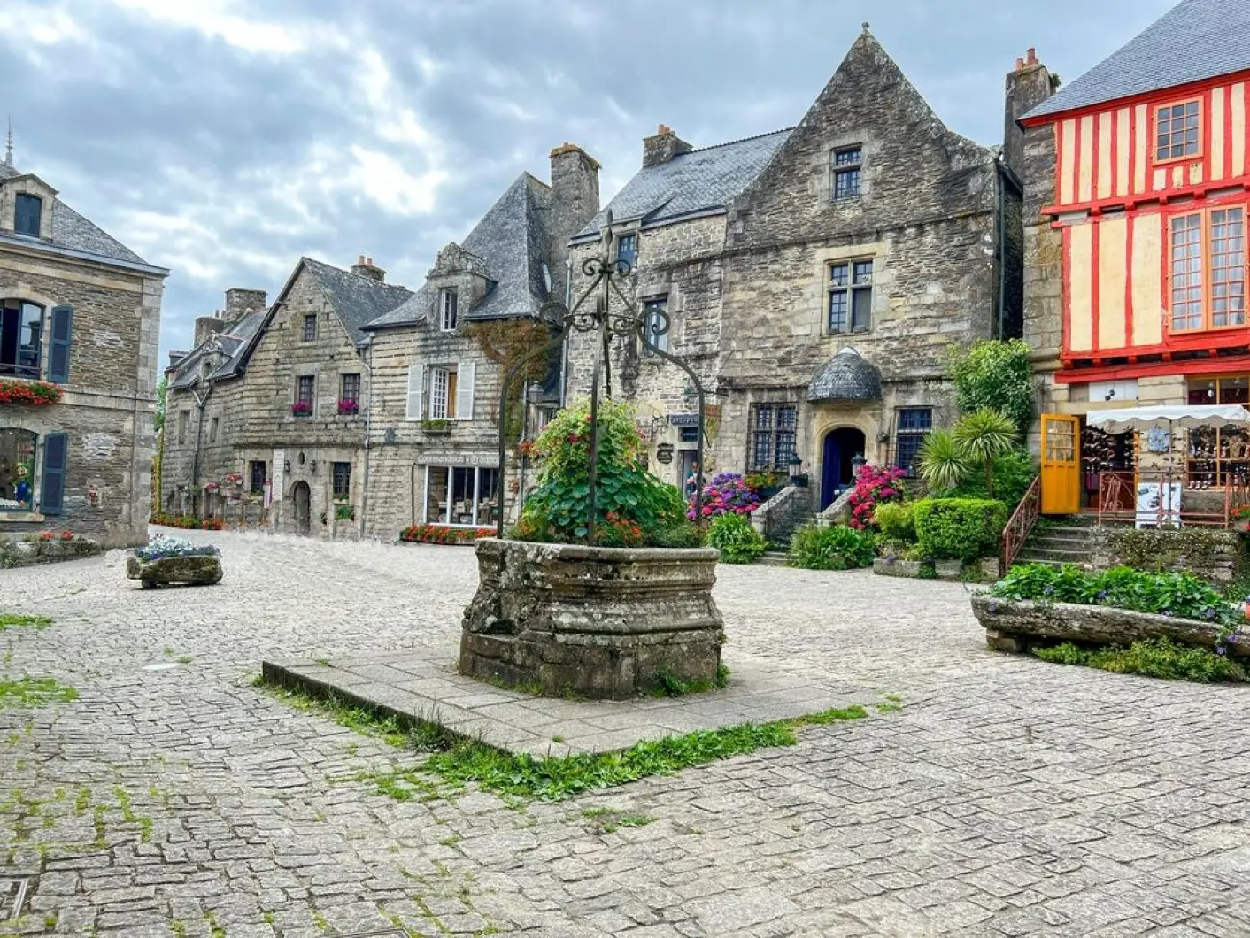 Historic stone buildings and well surround a charming medieval square in the French village of Rochefort-en-Terre.
