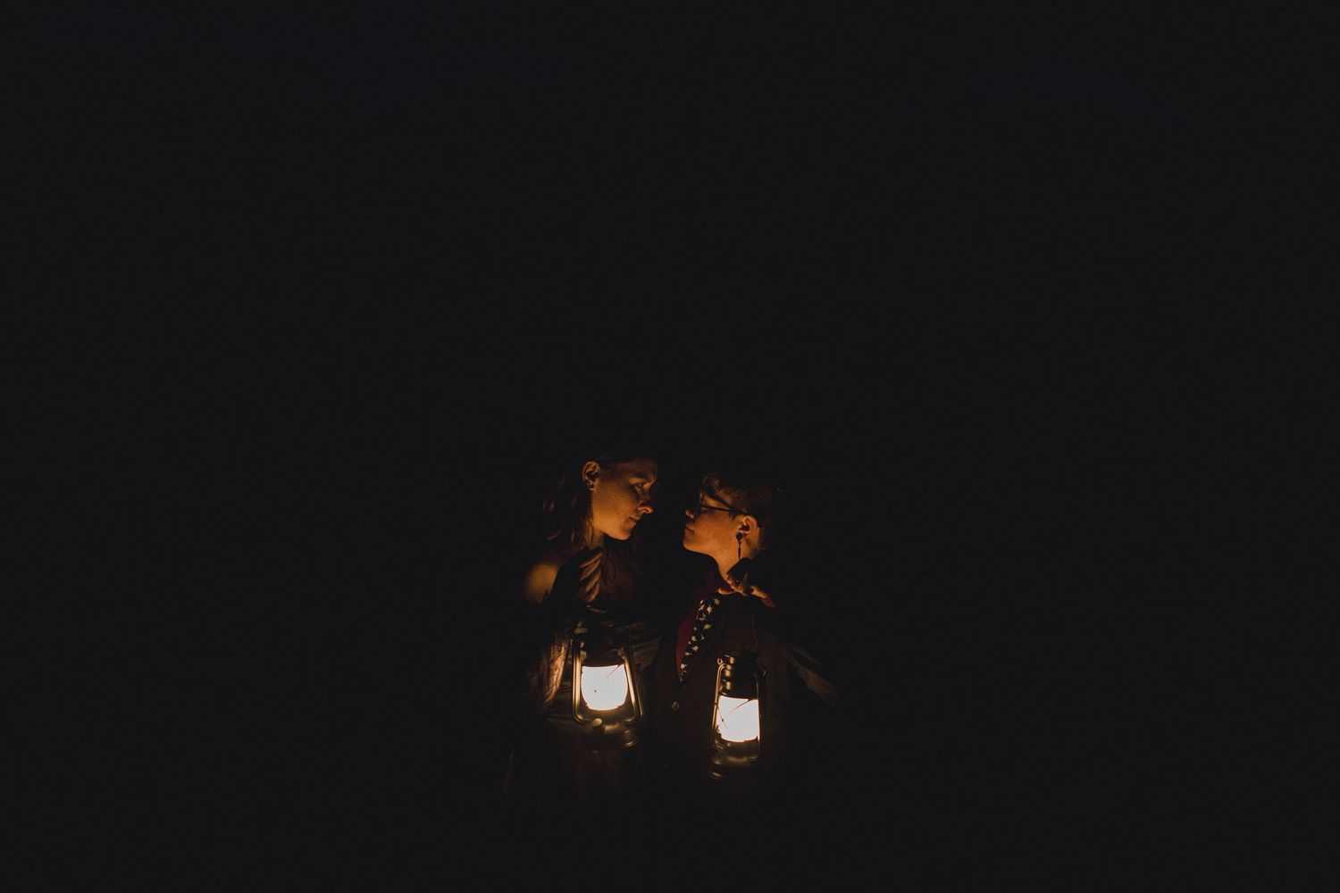 Two glowing lanterns illuminate a dark night scene, creating a warm and mysterious ambiance against the black background.