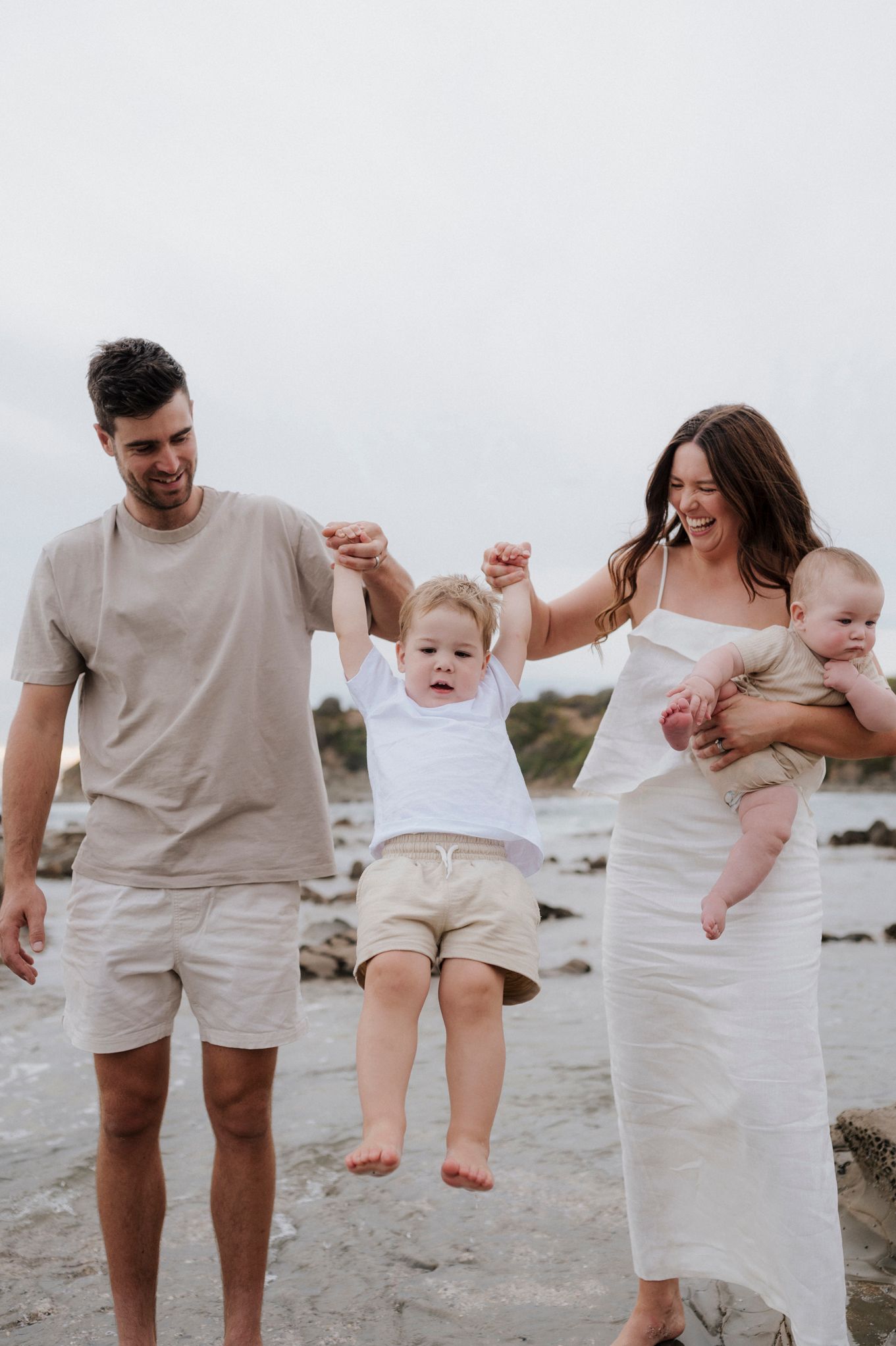 Parents swinging child between them while enjoying beach day.
