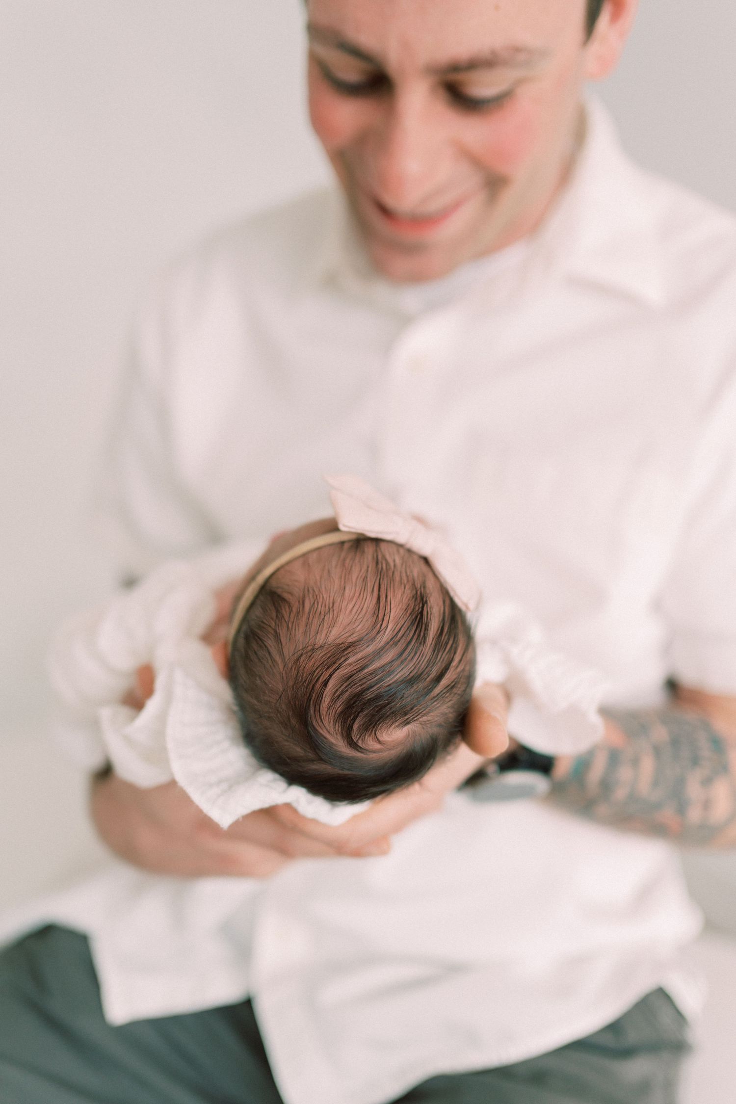 Overhead view of parent in white shirt holding sleeping newborn baby with soft brown hair on top.