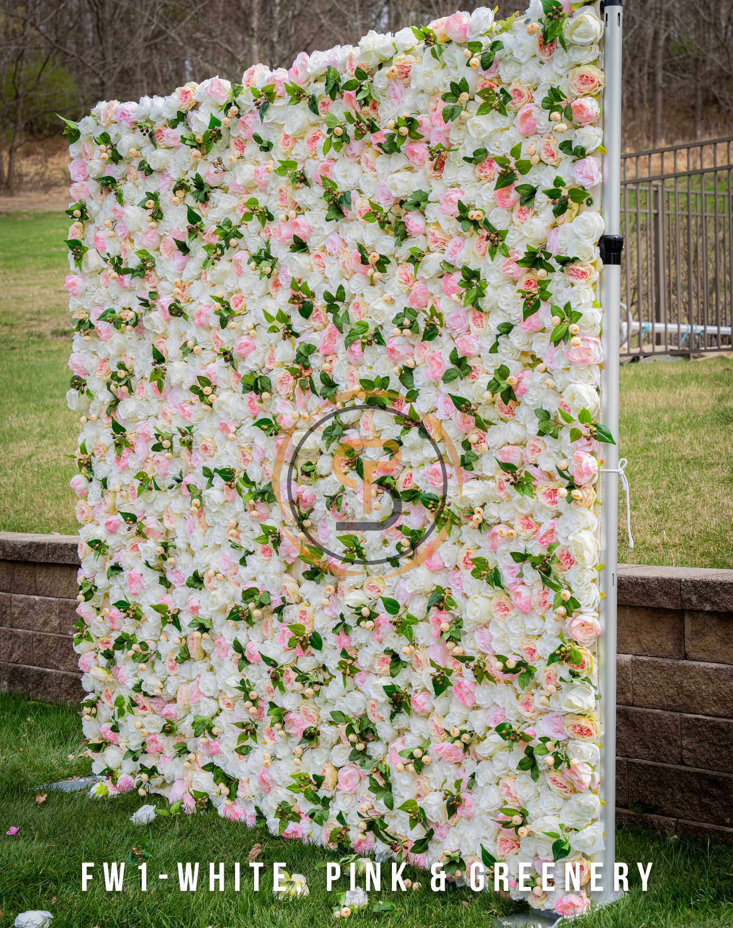 White and pink floral wall backdrop with circular logo and green foliage accents.