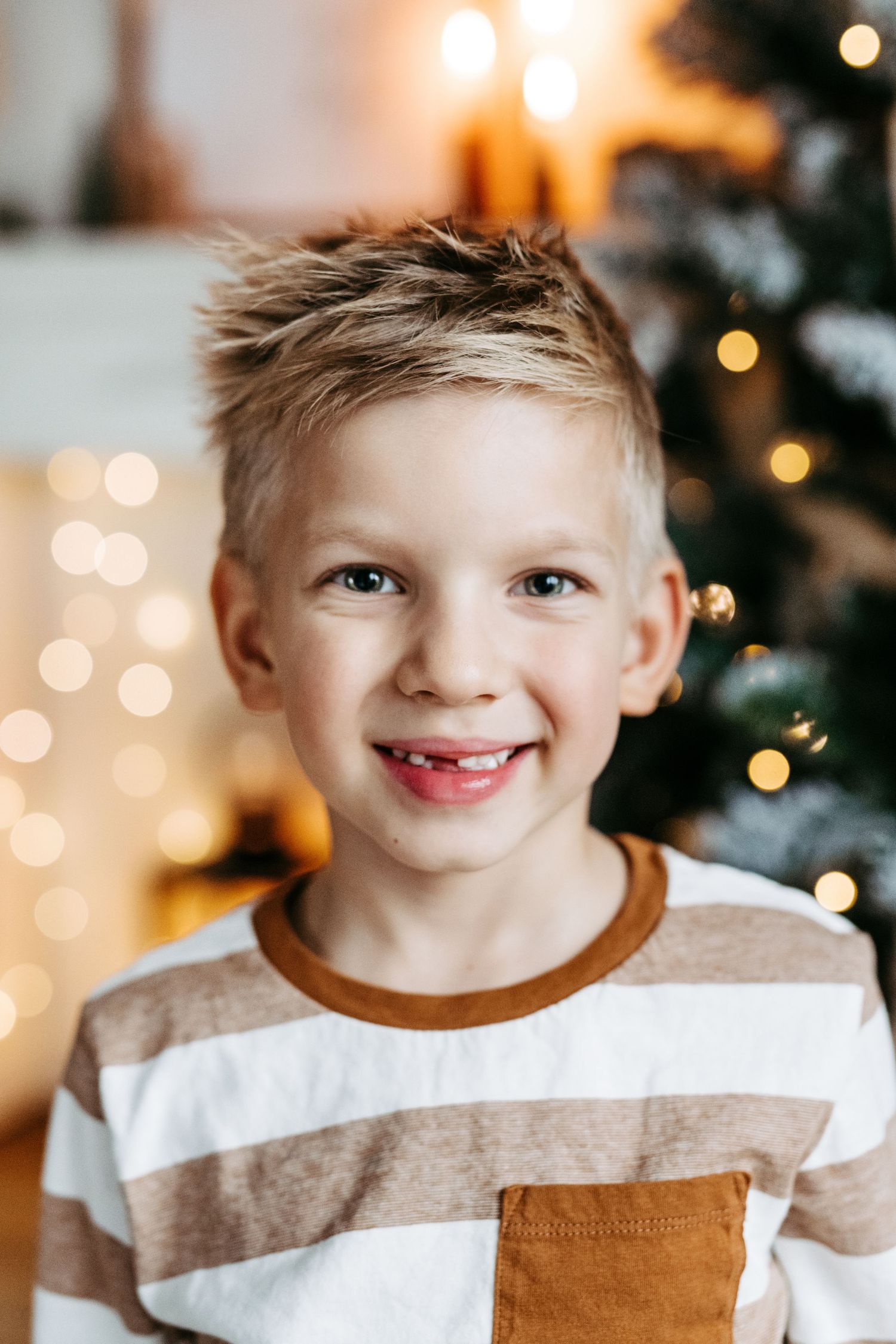 A festive holiday portrait with bokeh lights and a decorated Christmas tree in the background.