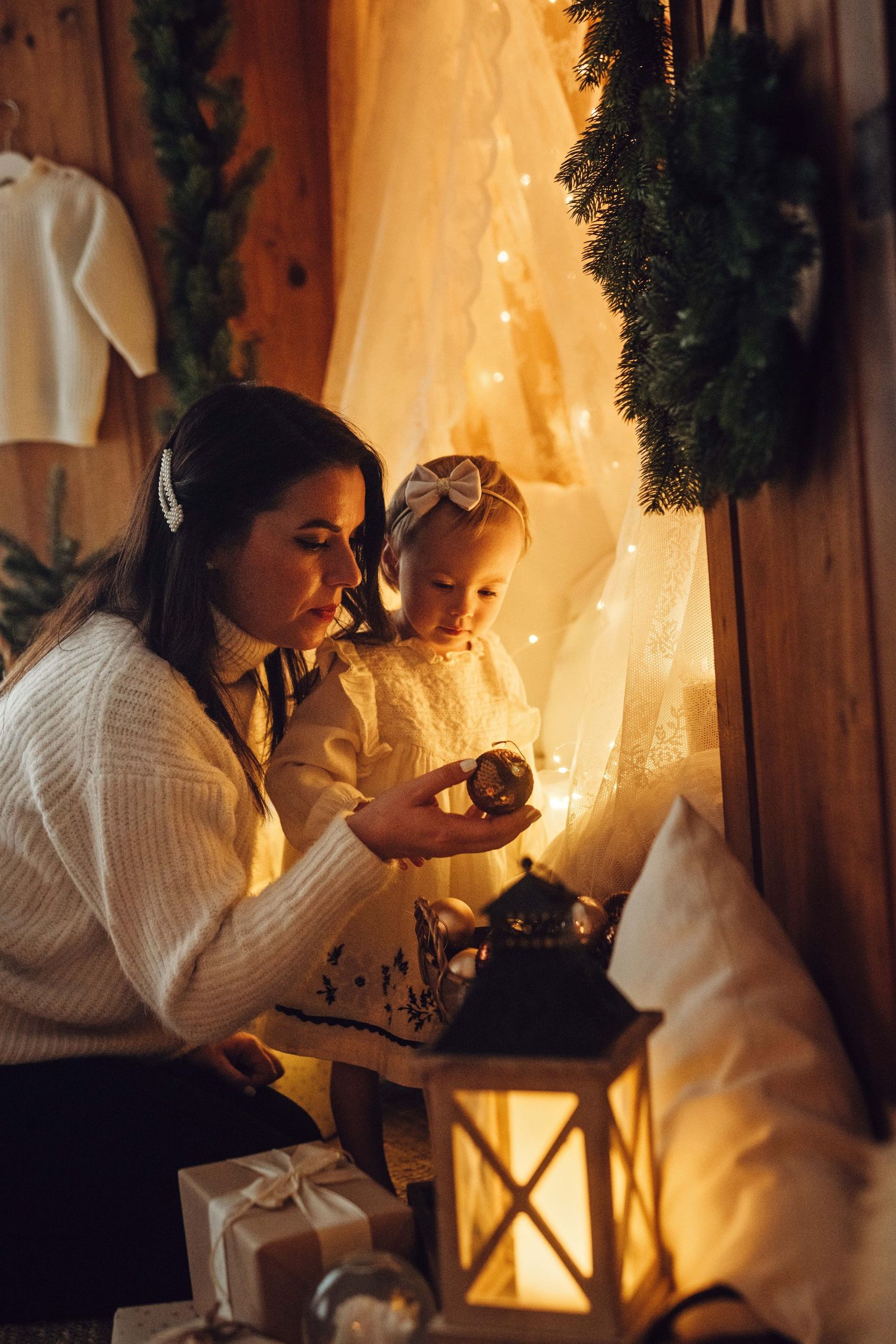A cozy holiday scene with a lantern glowing by Christmas lights and wrapped presents.