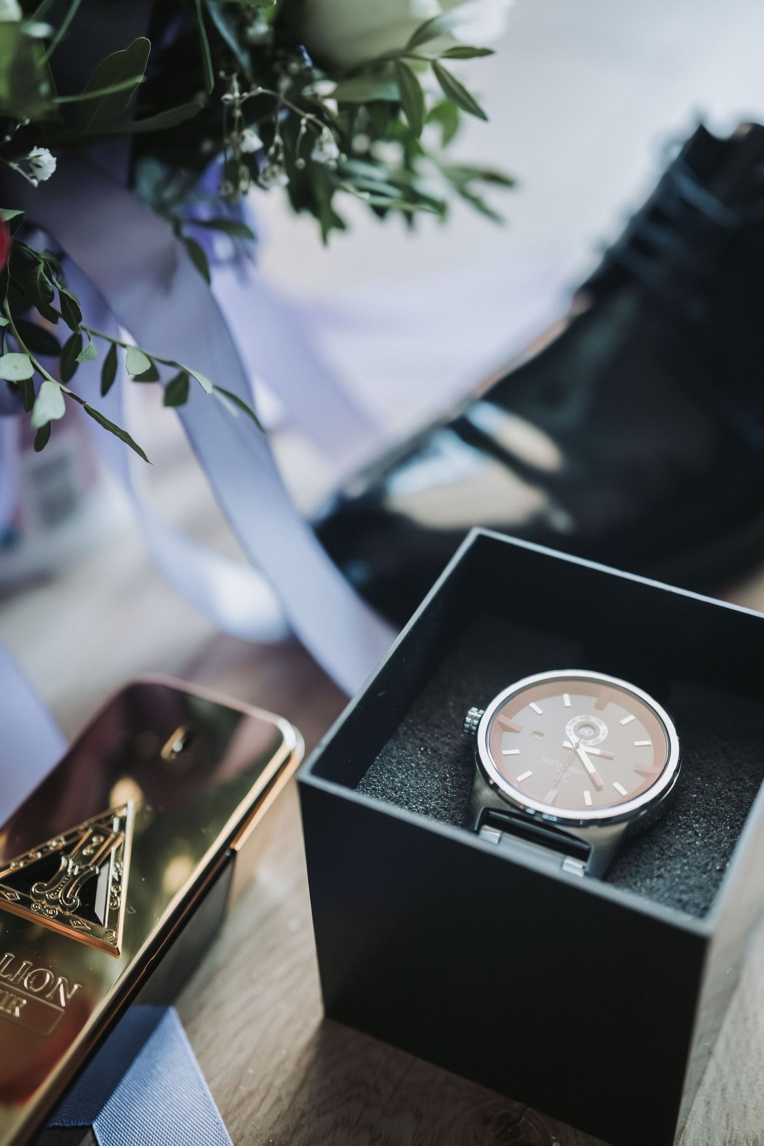 Wedding details featuring an elegant watch in a black box next to wedding accessories.