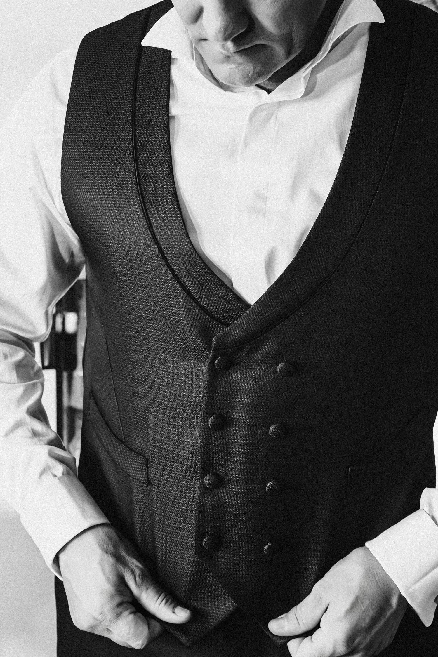 Close-up detail shot of a classic double-breasted black formal vest over white dress shirt.
