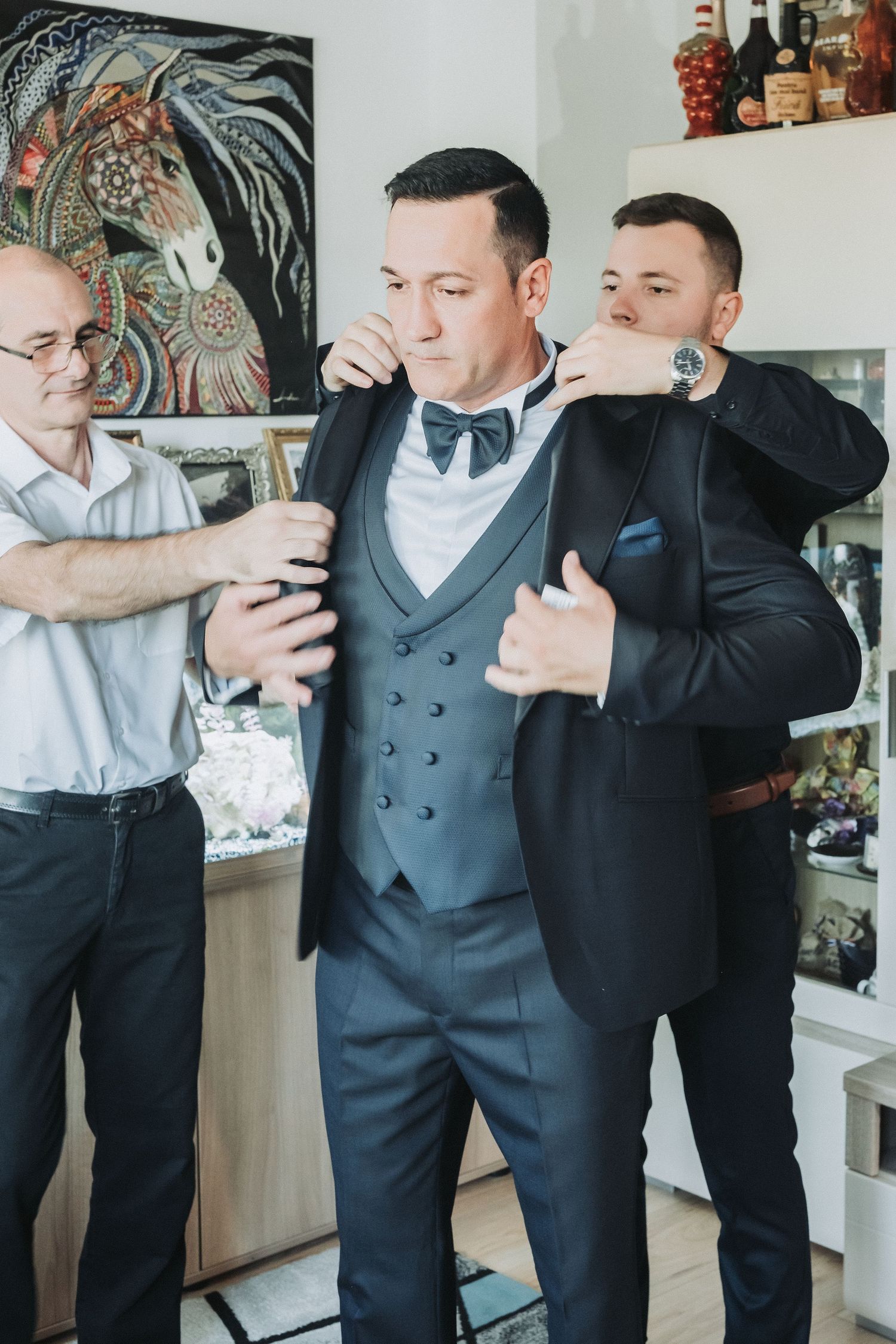 Wedding party assists with final preparations of formal attire before ceremony.
