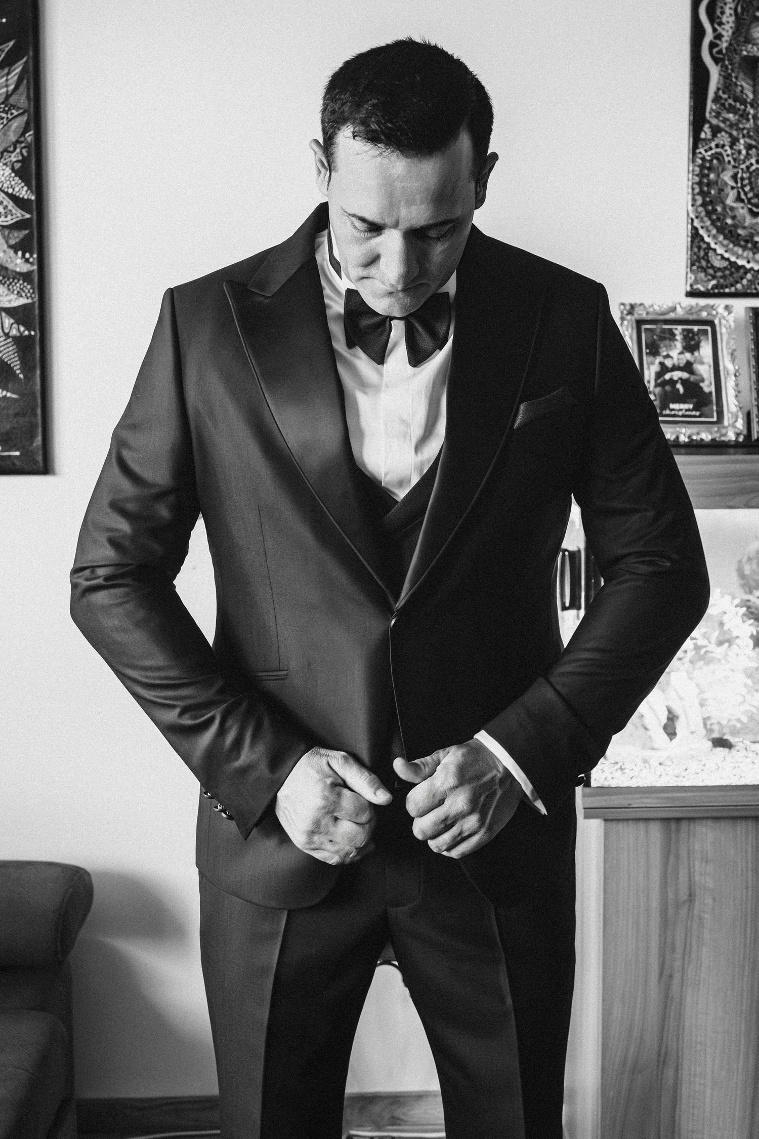 Classic black and white portrait of formal attire adjustments before wedding ceremony.
