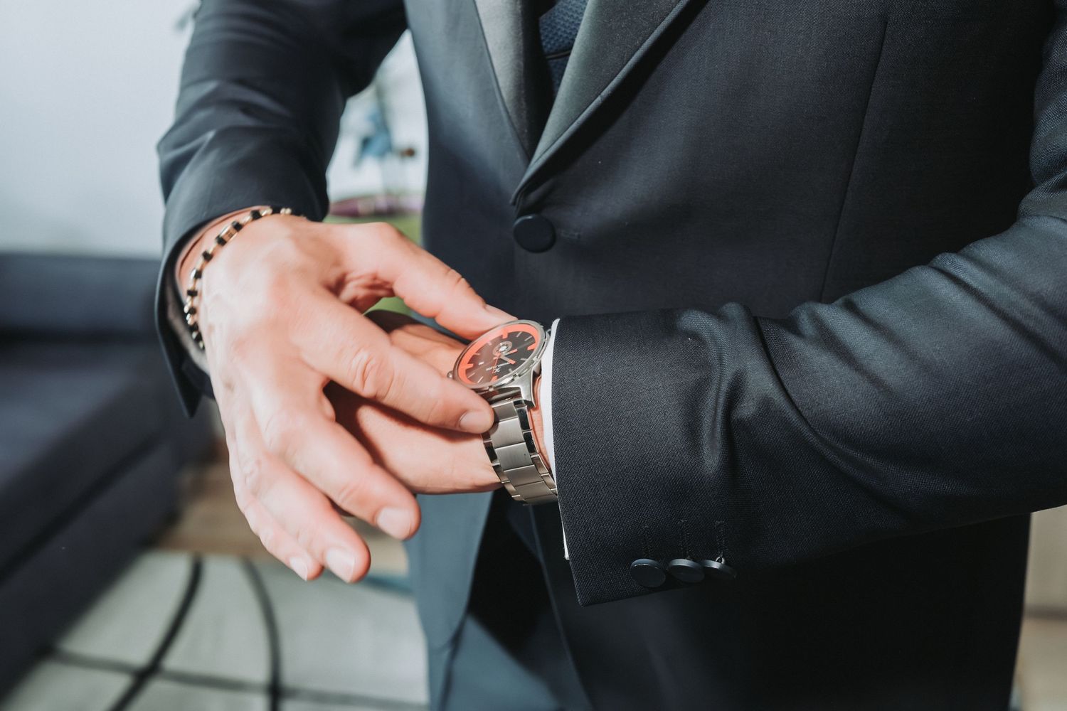 Detail shot of hands adjusting a watch while wearing formal wedding attire.
