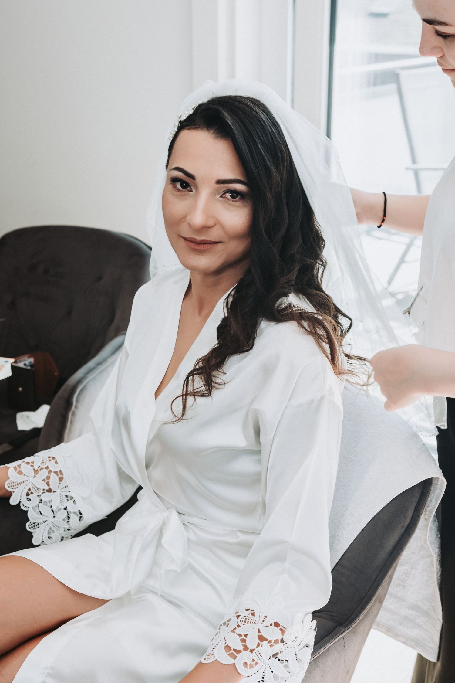 Person in white robe with lace details getting ready during wedding preparations.