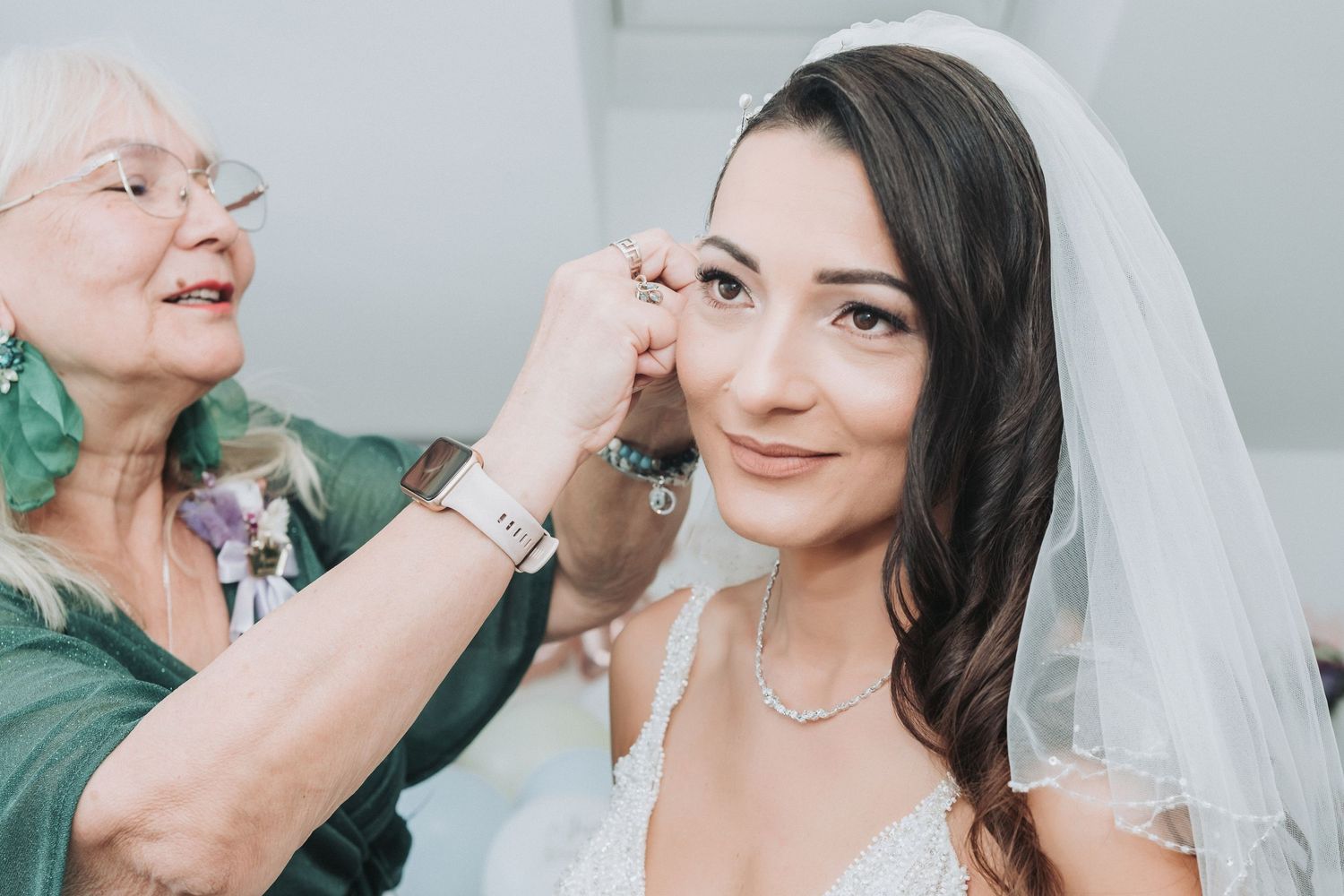 A person having her final wedding makeup touches applied while wearing a bridal veil.