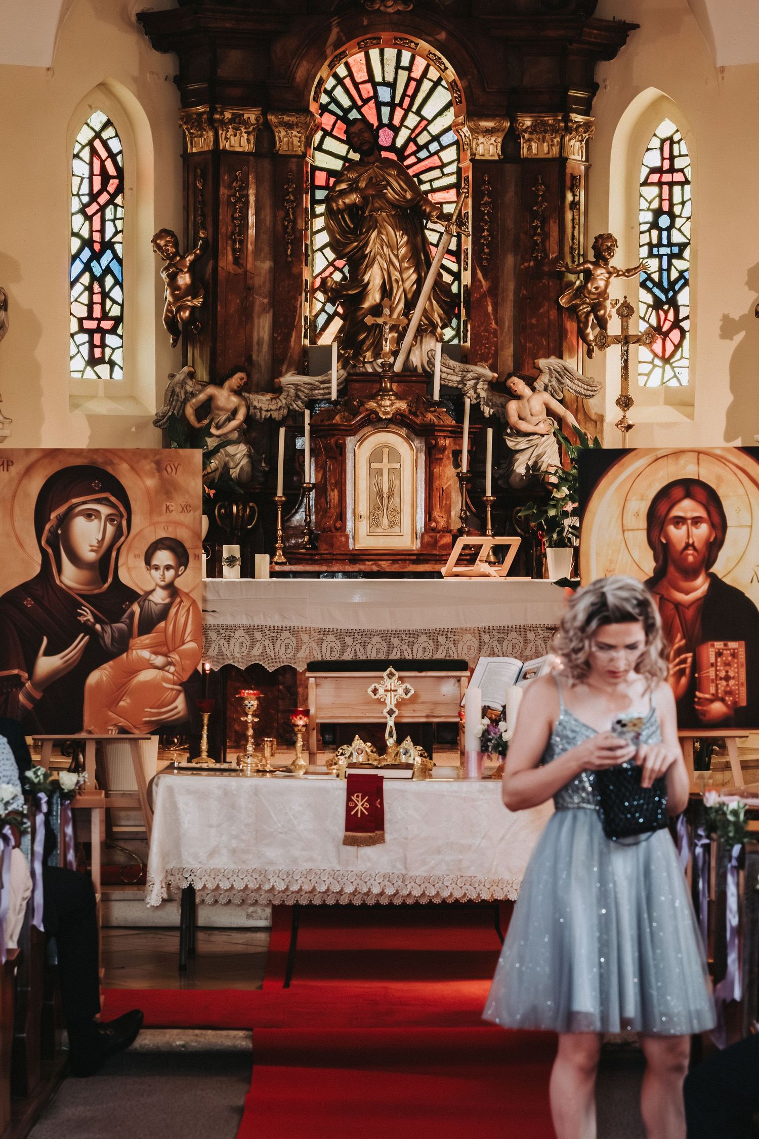 Ornate church altar with stained glass windows and religious icons in warm lighting.