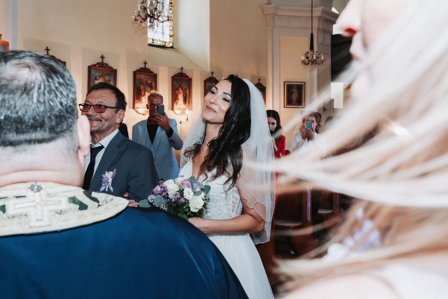 Wedding ceremony candid showing guests and decor in a traditional church setting.