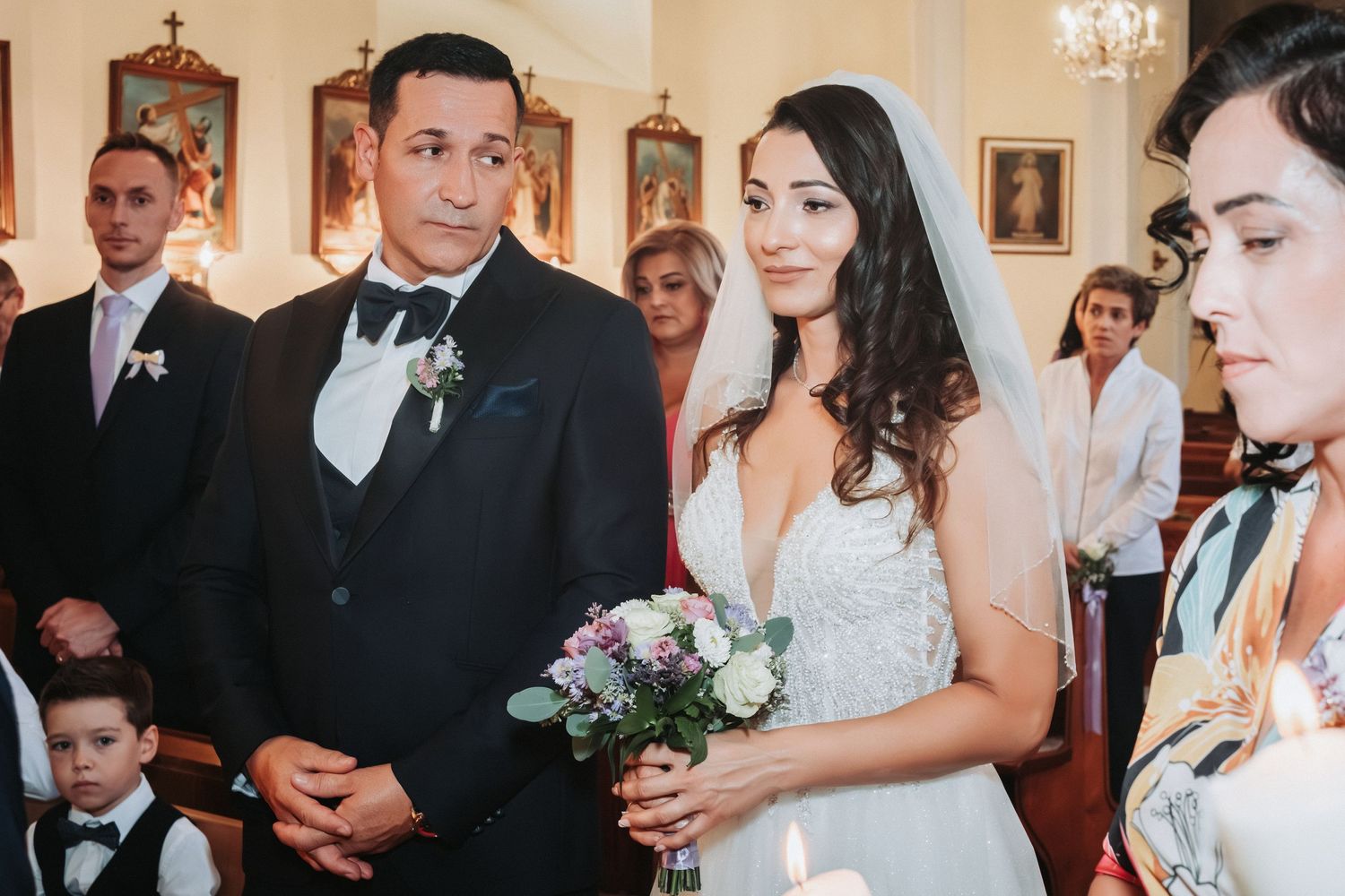 Wedding ceremony in progress with couple standing at the altar surrounded by guests in a church.