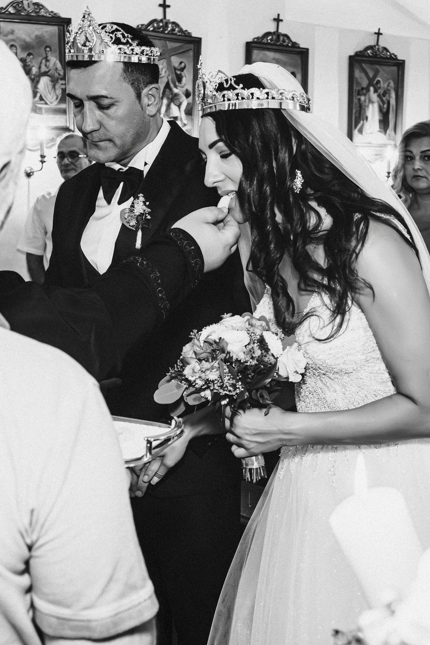 Newlyweds wearing crowns during traditional religious wedding ceremony in church with icons.