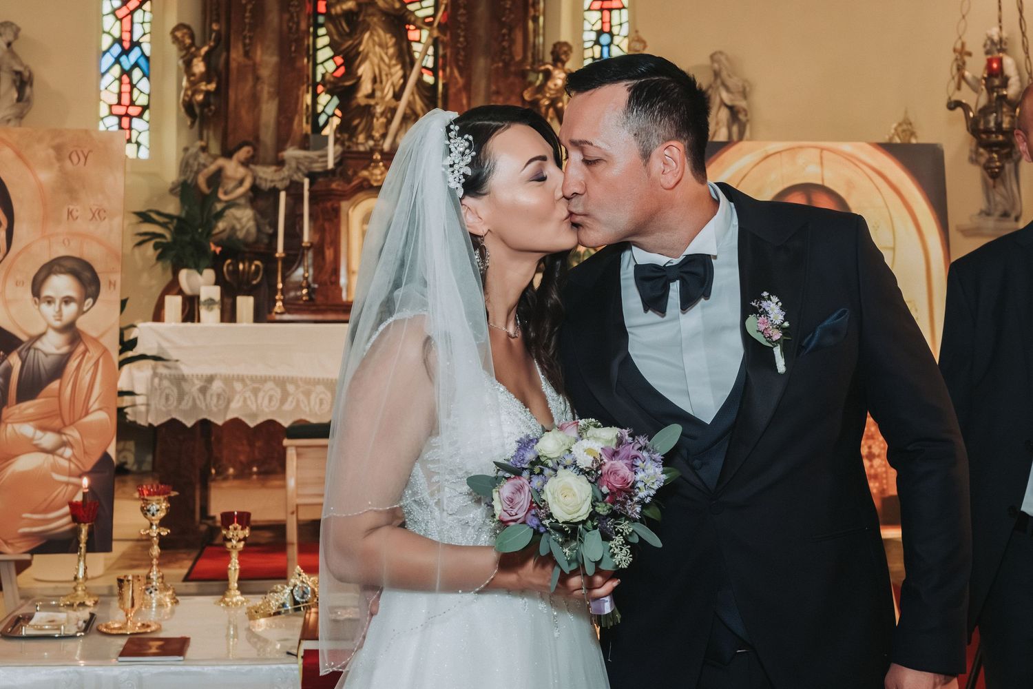 Newlyweds share romantic kiss at church altar during wedding ceremony.