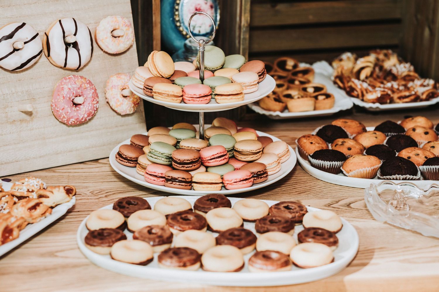 Dessert table with various plates of donuts, macarons and sweet treats at wedding reception.