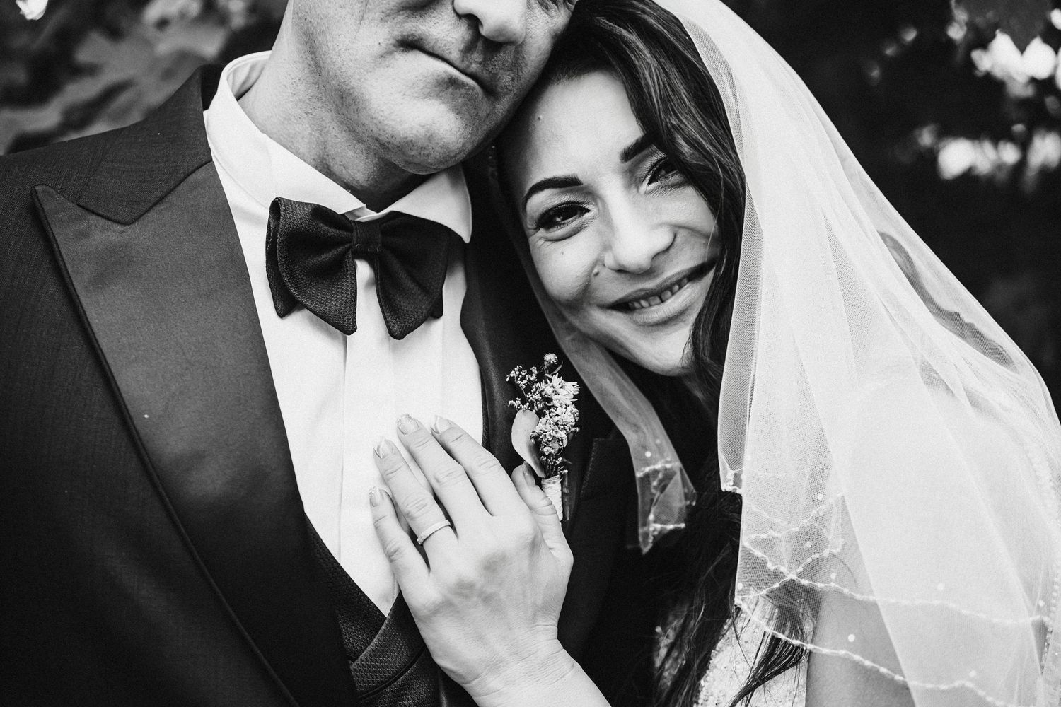 Black and white close-up of a happy couple sharing an intimate moment under the bride's veil.