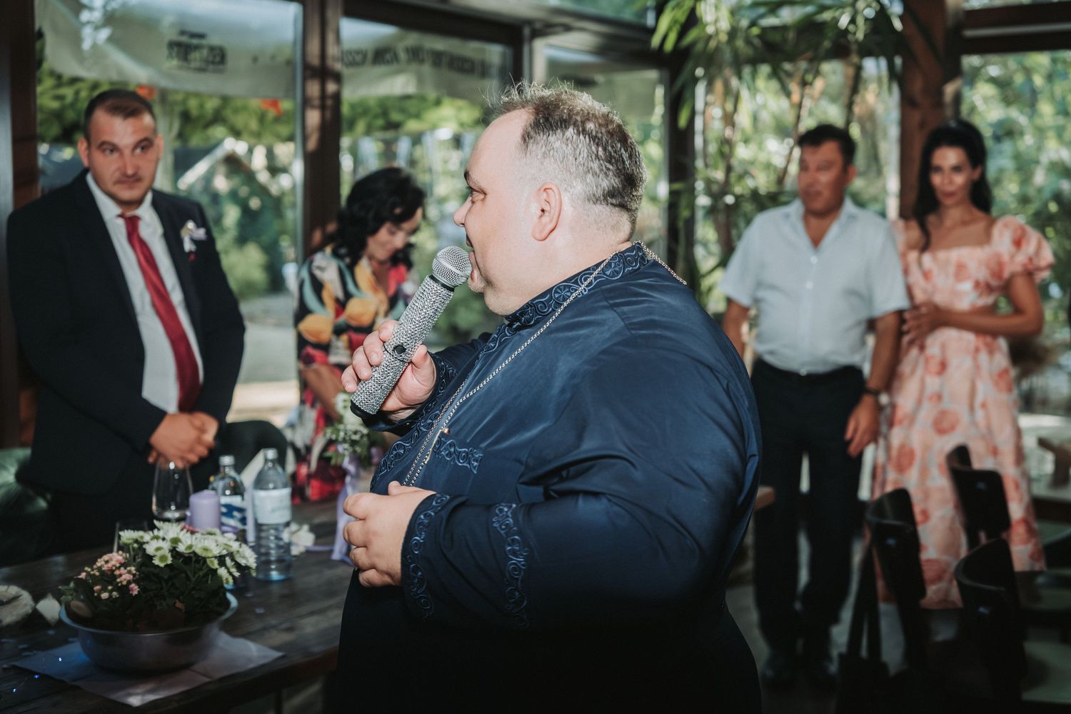 Wedding guests listening to speeches during an indoor reception.