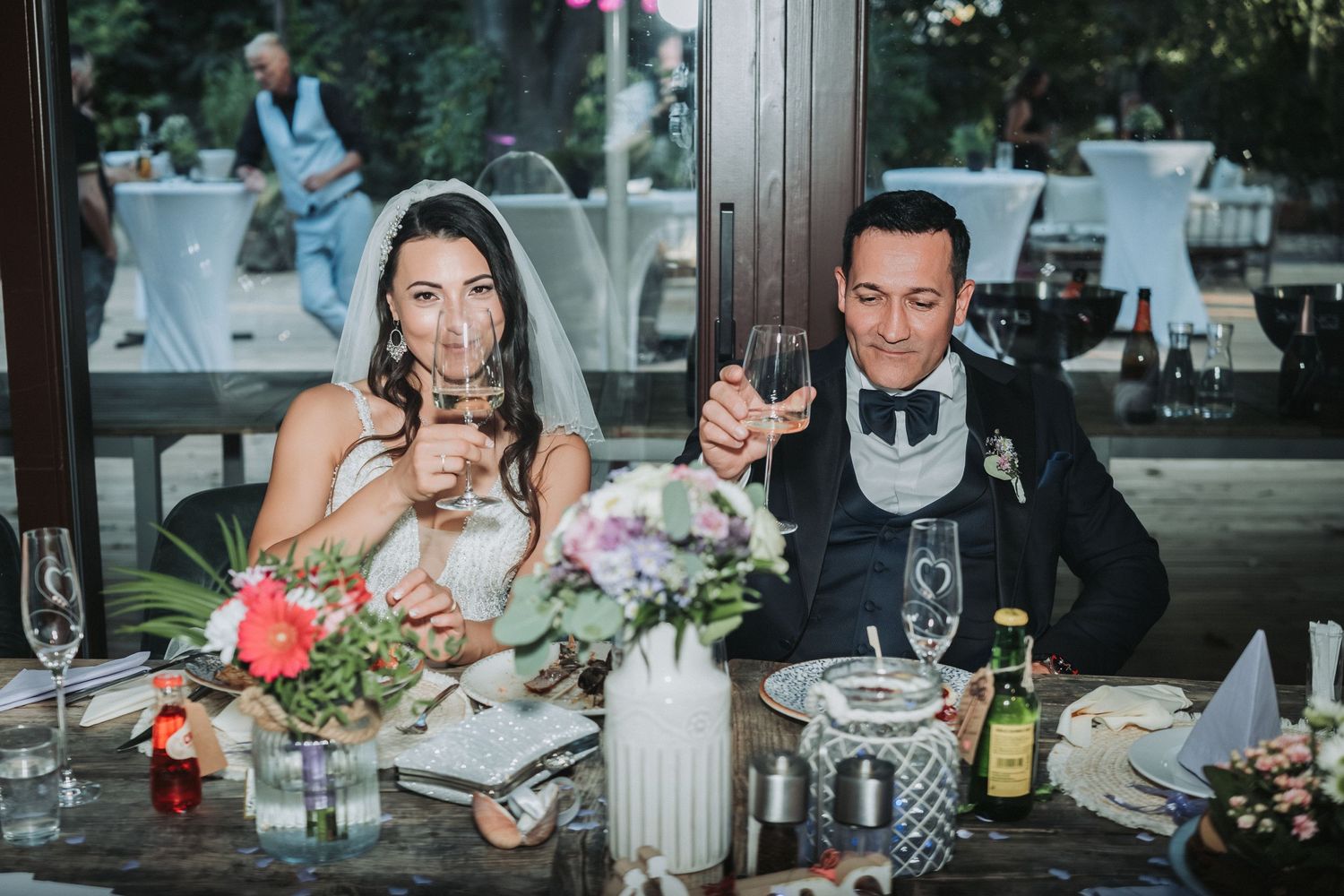 Newlyweds enjoy drinks at their decorated reception table.