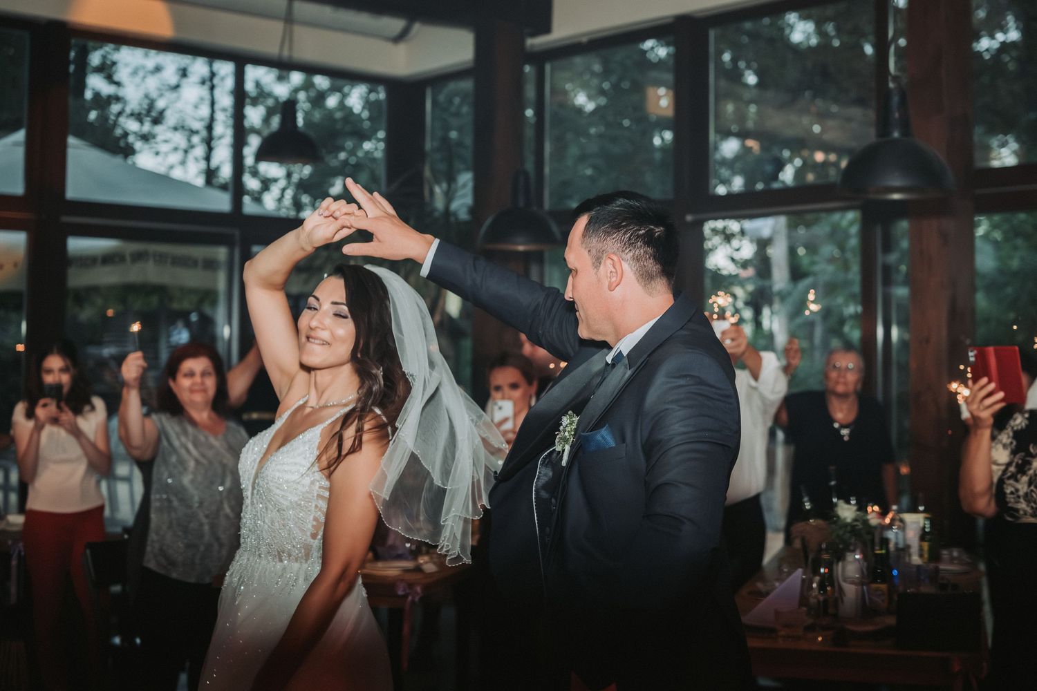 A couple performs their first dance at a wedding reception with guests watching in the background.