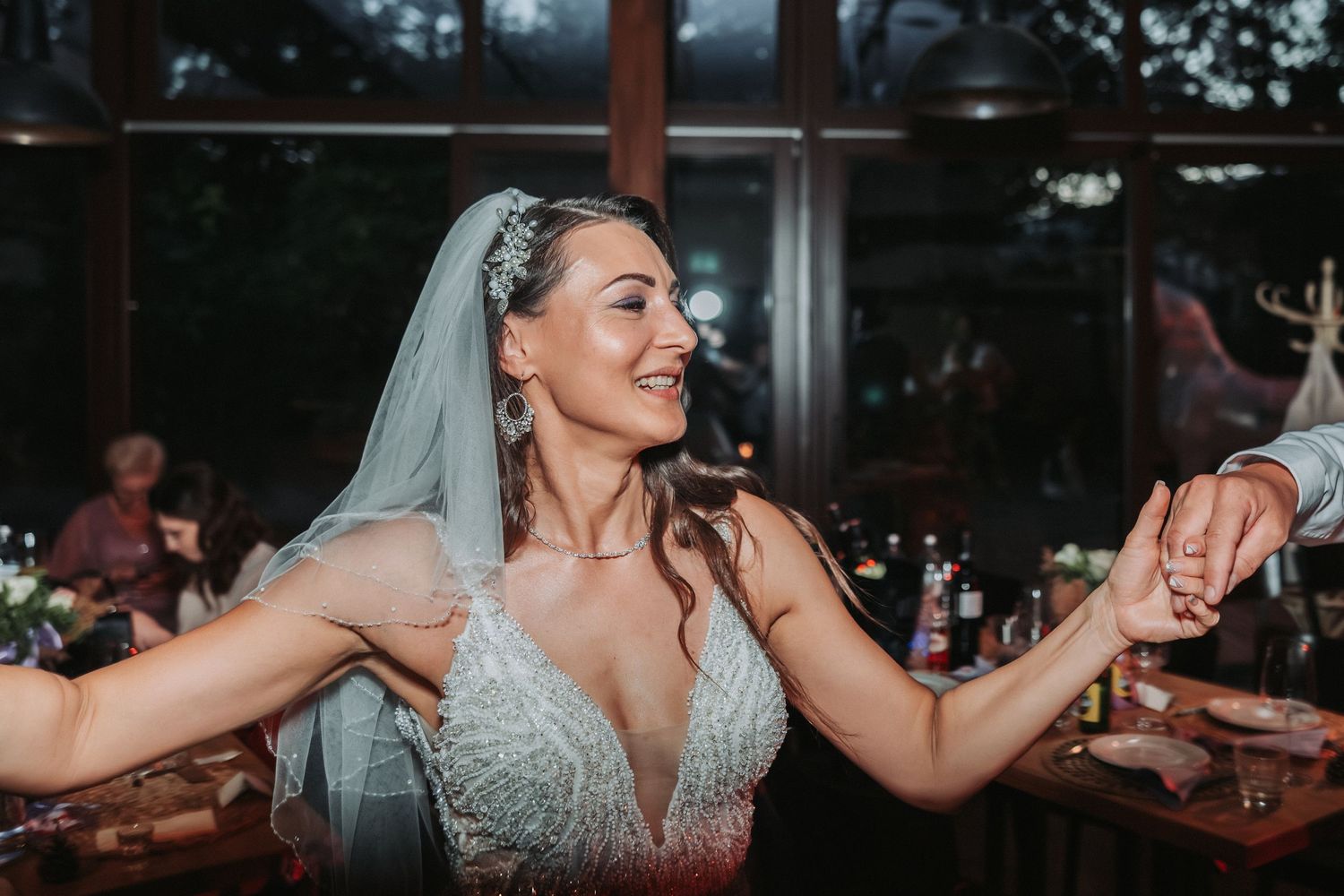 A bride in a sparkly white dress dances energetically at her wedding reception.