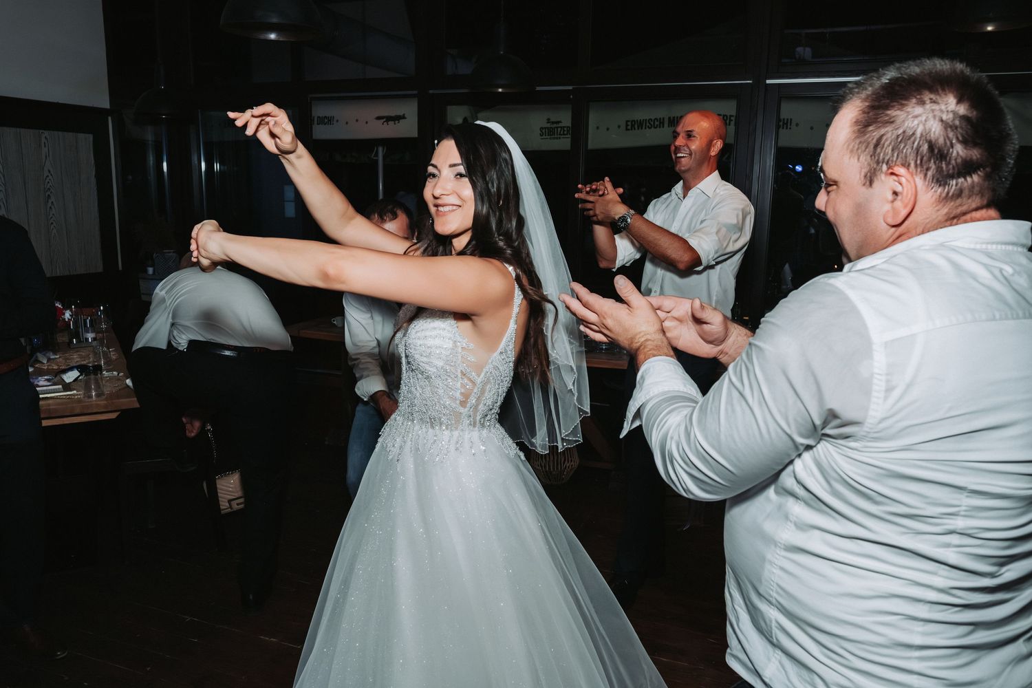 A bride in a white gown dances with guests during the wedding reception.
