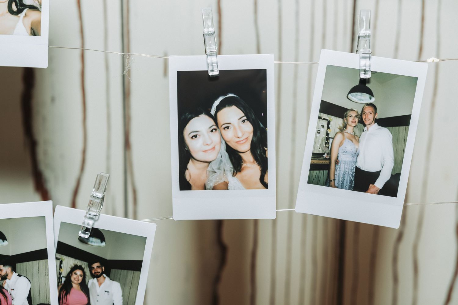 Polaroid-style photos hanging on strings display wedding day memories.