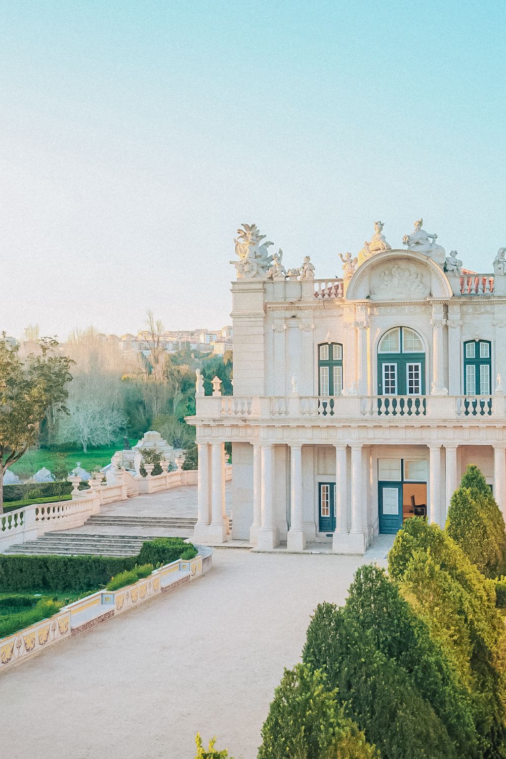 Elegant queluz palace in Portugal with columns and ornate details against a light blue sky. captured by a Portugal wedding photographer