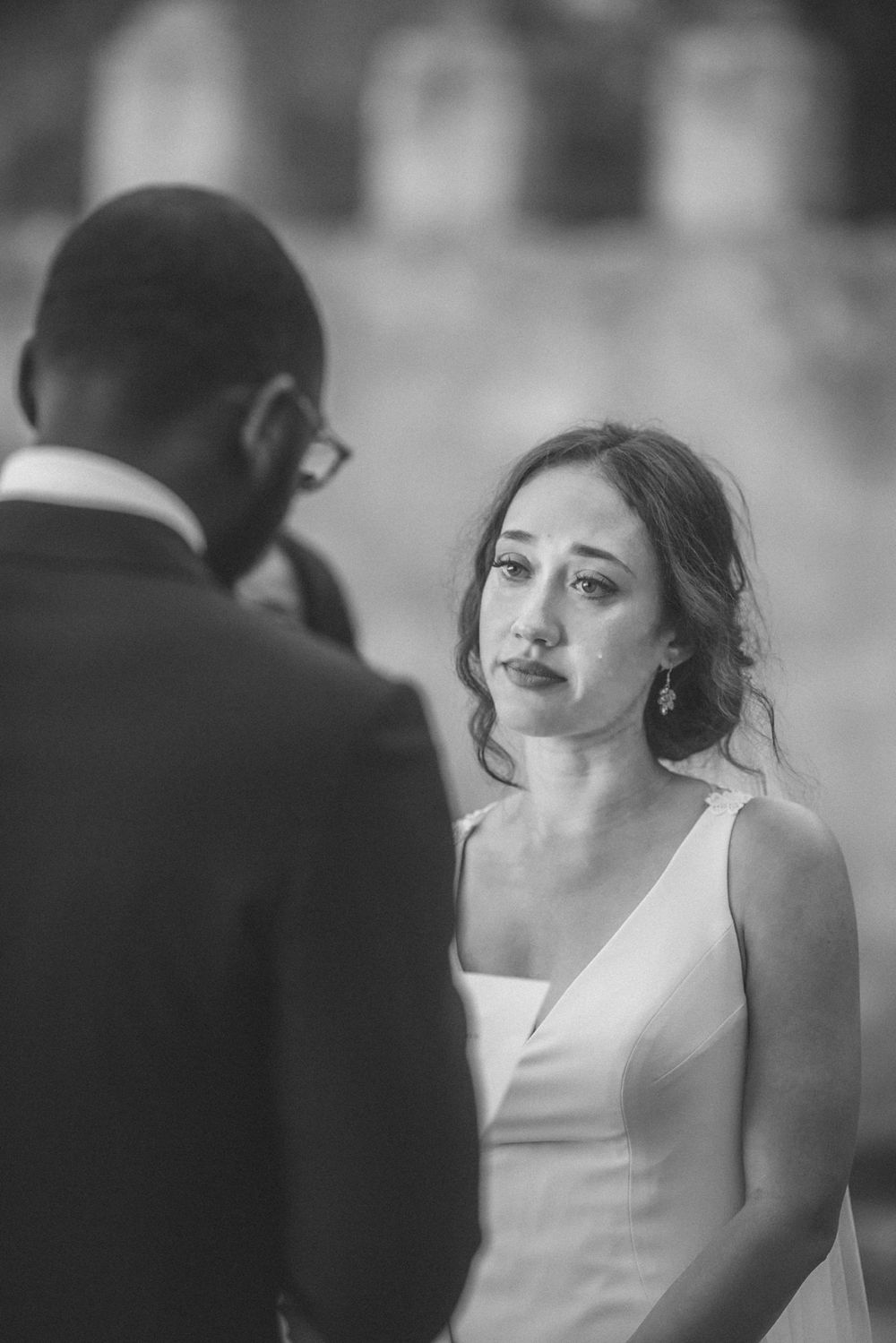 An emotional black and white wedding ceremony moment captured during the exchange of vows at nuncio garden of penha longa, portugal