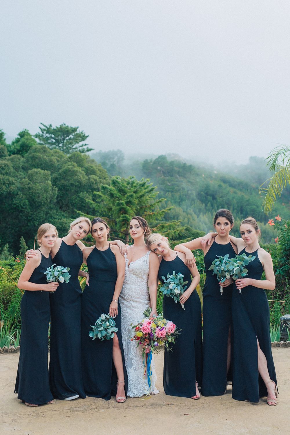 Wedding party in black dresses poses with bride in white gown at Monserrate palace. captured by a Portugal wedding photographer