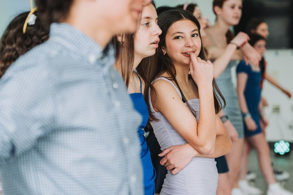 A group of young people standing together and chatting in a casual indoor setting.