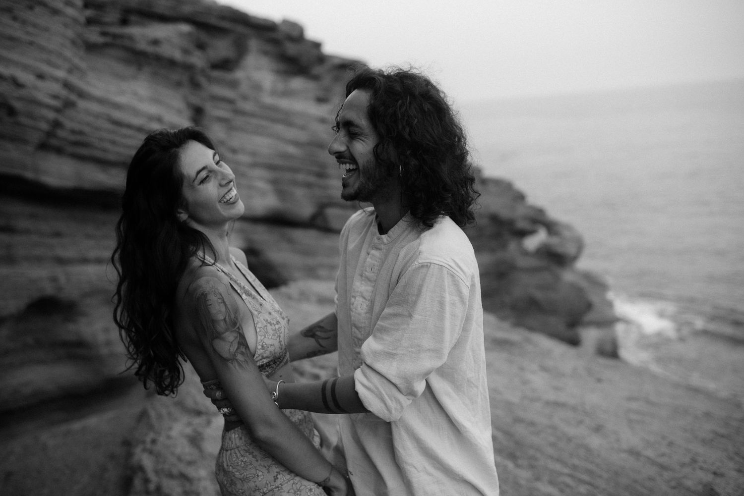 Romantic black and white photo of couple on seaside cliff.
