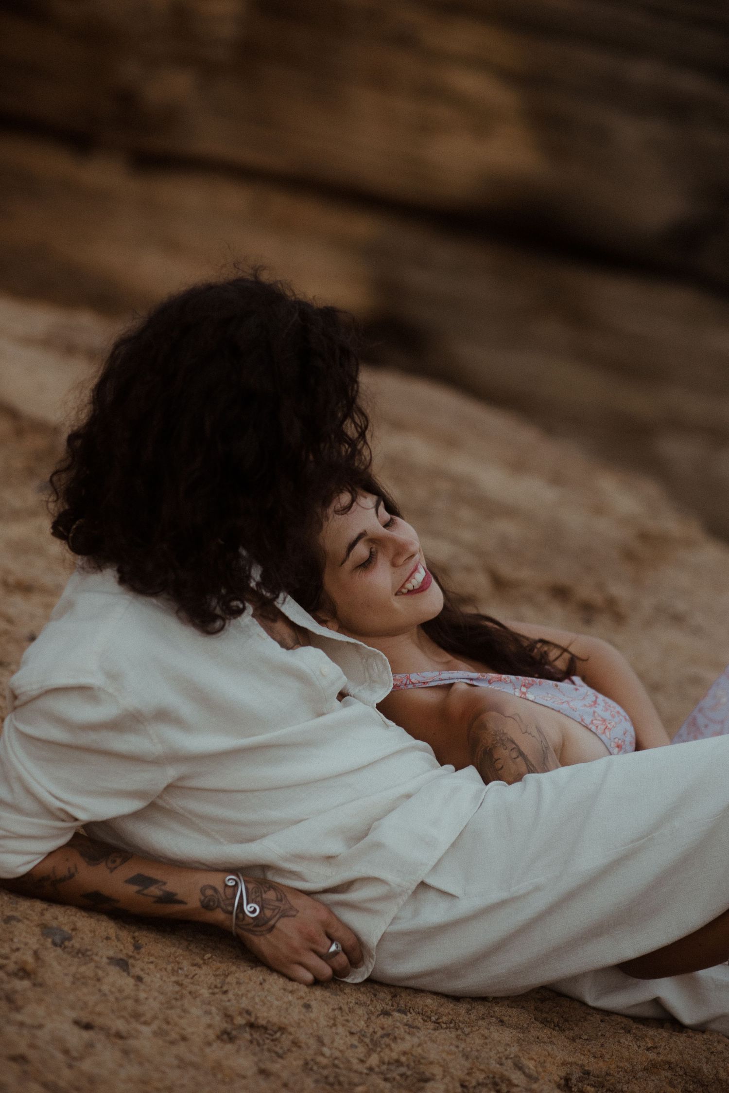 Intimate moment captured between couple on rocky coastal terrain.