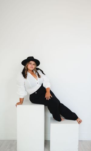 Minimalist fashion photo with black hat and white shirt against white background.