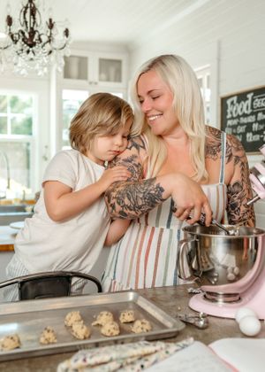 A baking scene in a bright kitchen with a stand mixer and cookies on a baking sheet.