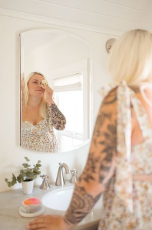 A mirror reflection showing a floral patterned top and bathroom decor.