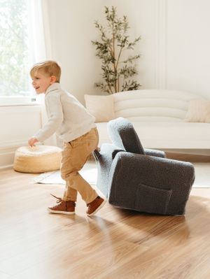 Child playing near furniture in bright minimalist room with hardwood floors.