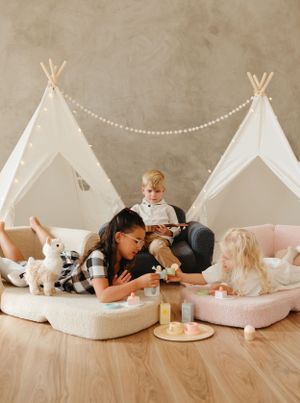 Playdate scene with teepee tents, floor cushions and stuffed animals in neutral tones.