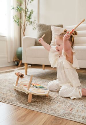 A soft neutral playroom scene with educational toys on a patterned rug.