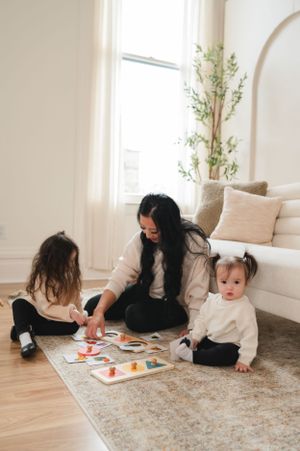 A cozy living room scene with educational toys and games spread on a neutral rug.