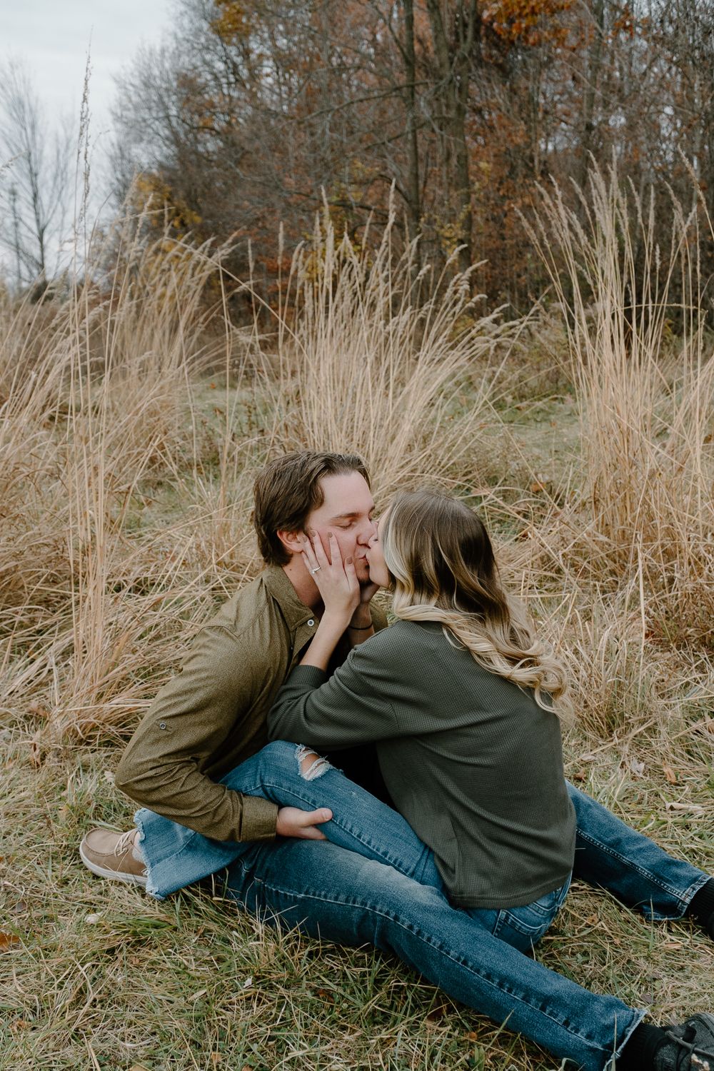 A romantic moment shared between a couple sitting in tall autumn grass.