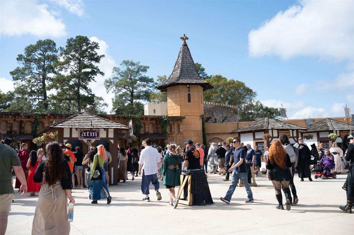 Crowd of visitors walking through Fantasyland at Walt Disney World theme park on a sunny day with turret tower visible.