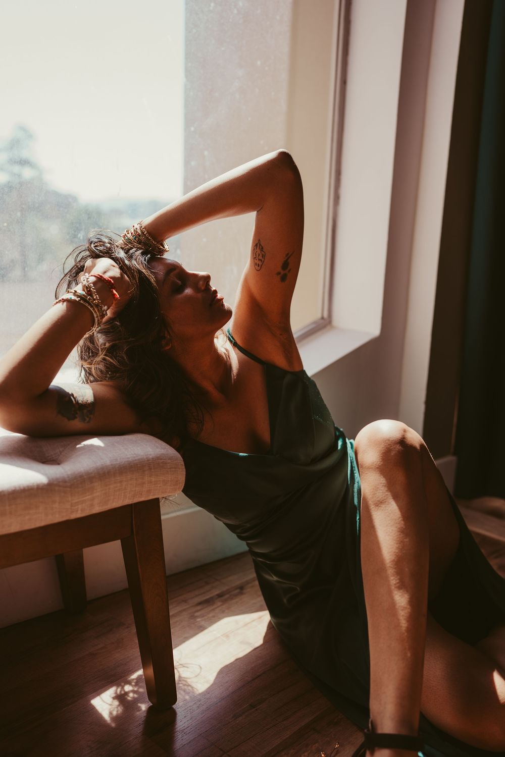 Artistic silhouette photograph shows person reclining in moody window lighting with vintage warm tones.