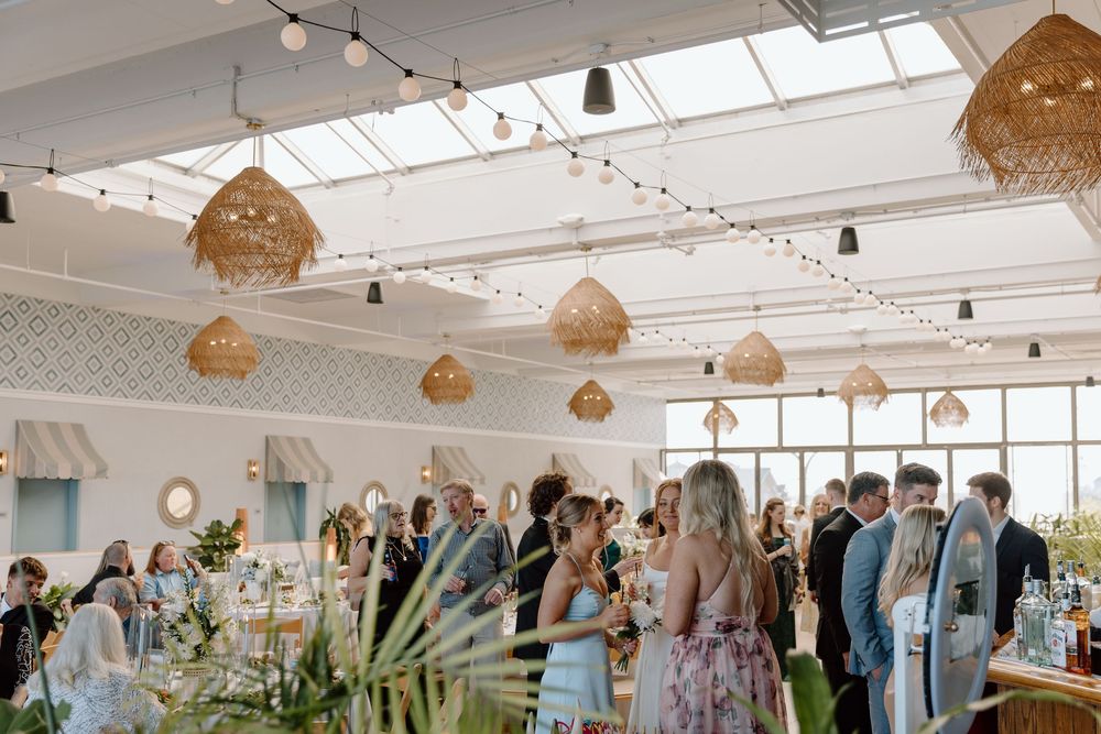 Light-filled reception venue decorated with woven pendant lamps and string lights for an elegant wedding celebration.