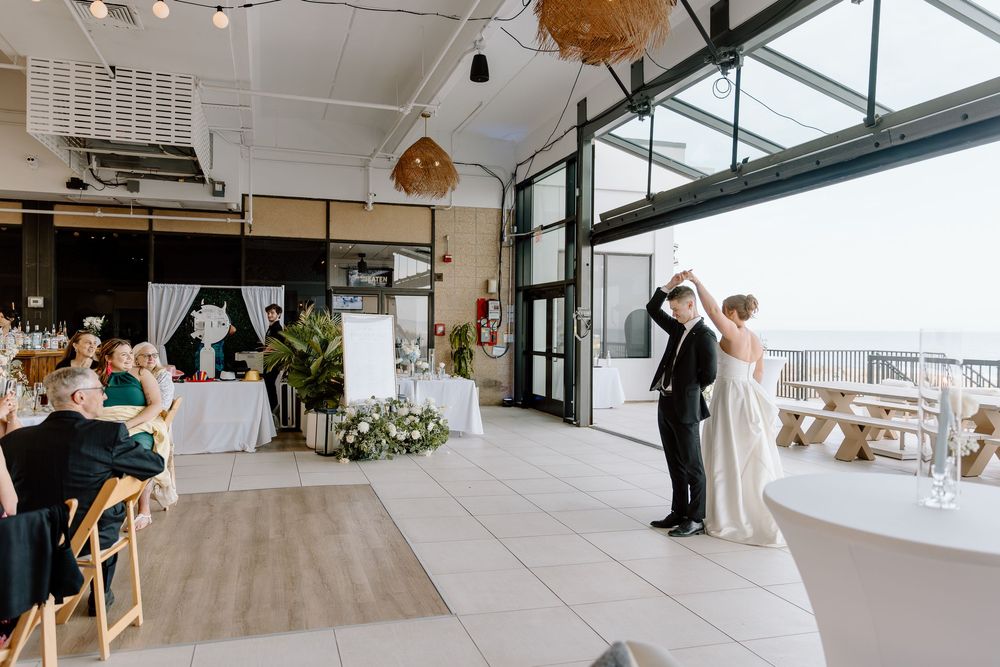 Modern wedding ceremony in a bright venue with floor-to-ceiling windows and woven pendant lighting.