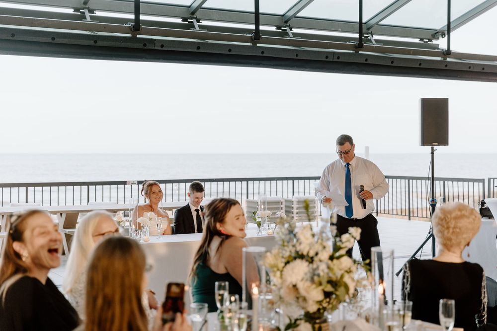 Wedding reception guests dancing together in an elegant indoor venue decorated with hanging pendant lights.